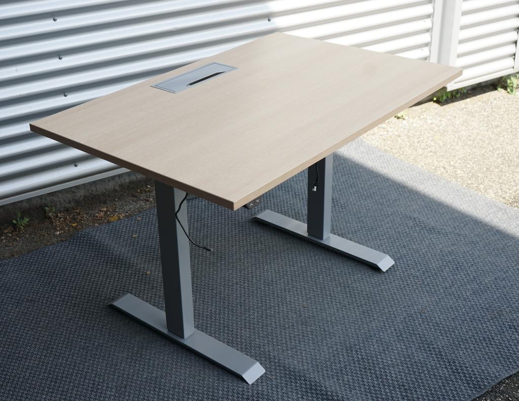 Conset elektrisk hæve-sænkebord 120x80 i egetræ med kabelbakke og kabelgennemføring, set fra skrå vinkel.